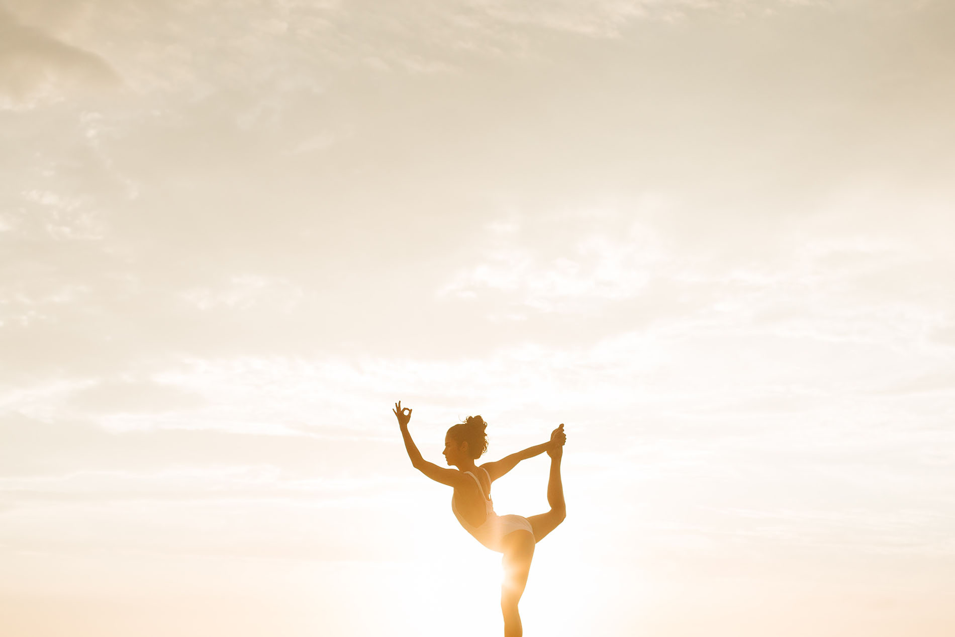 Femme en posture de yoga debout devant le soleil couchant