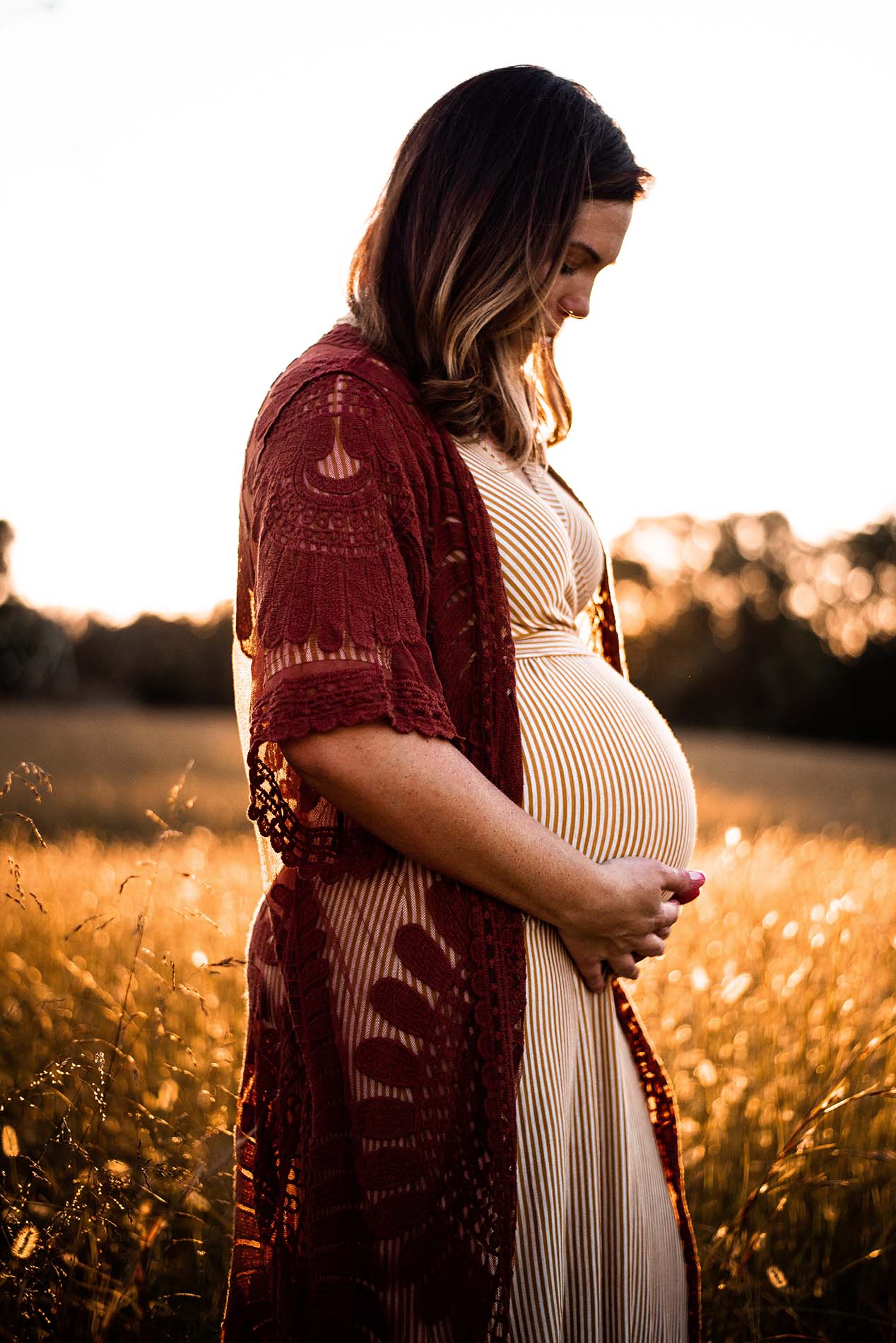 Femme enceinte au soleil couchant dans un champ
